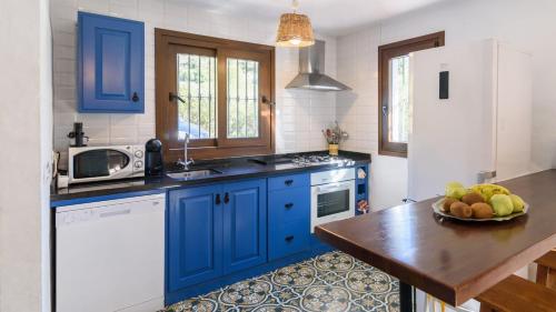 a kitchen with blue cabinets and a bowl of fruit on a table at Arroyo del Moro Gaucín by Ruralidays in Gaucín
