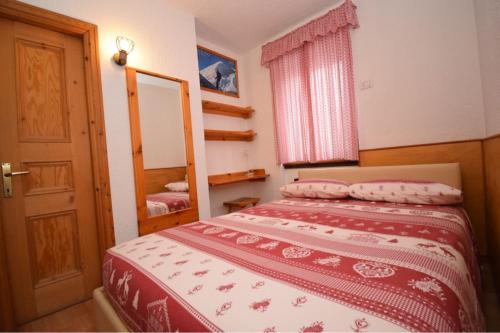 a bedroom with a bed with a mirror and a door at Grazioso appartamento vicino al centro in Livigno
