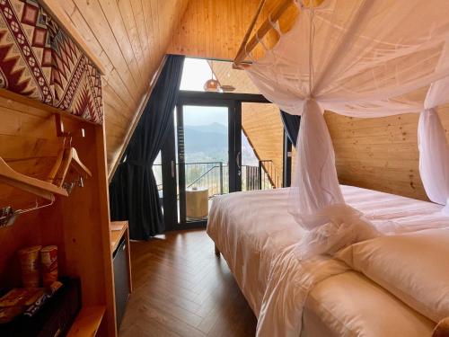 a bedroom with a bed and a large window at Le Champ Tu Le Resort Hot Spring & Spa in Yen Bai