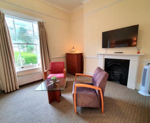 a living room with two chairs and a fireplace at The Wellington Hotel - B&B in Ventnor