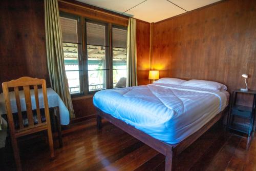 a bedroom with a bed and a chair and a window at SeeSea Thai wooden house on beachfront in Prachuap Khiri Khan