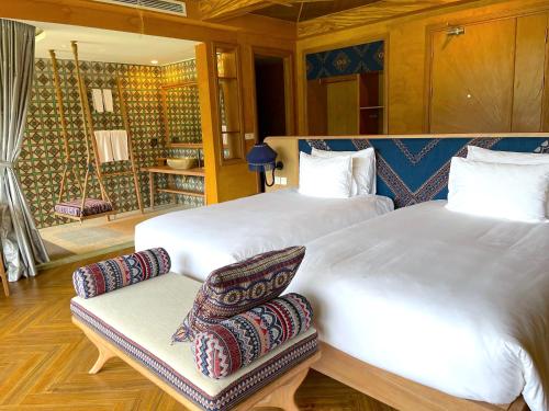 a bedroom with two beds and a chair in it at Le Champ Tu Le Resort Hot Spring & Spa in Yen Bai