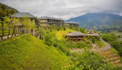 a house on top of a green hill at Le Champ Tu Le Resort Hot Spring & Spa in Yen Bai
