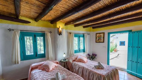 two beds in a room with blue windows at El Acebuchal - Casa Rosa Frigiliana by Ruralidays in Frigiliana