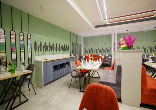 a restaurant with tables and chairs and green walls at Kovvuru Grand in Proddatūr