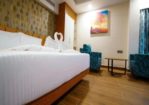 a bedroom with a white bed and two chairs at Kovvuru Grand in Proddatūr