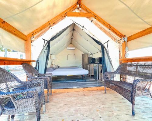 a tent with chairs and a bed in it at Son's Rio Cibolo - Glamping Cabin #J Romantic Getaway on Gorgeous Cibolo Creek! in Marion