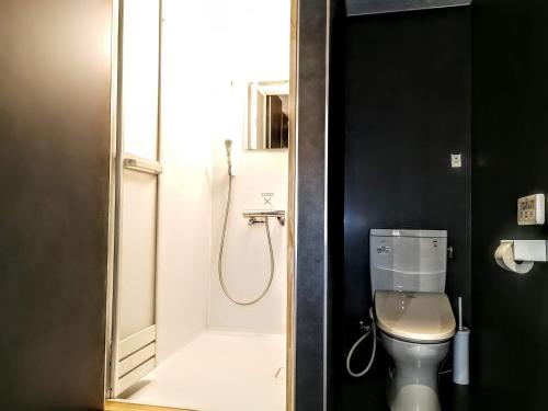 a bathroom with a shower and a toilet in it at Fujio Pension Madarao Apartment Hotel & Restaurant in Iiyama