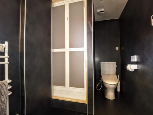 a bathroom with a toilet with a window in it at Fujio Pension Madarao Apartment Hotel & Restaurant in Iiyama