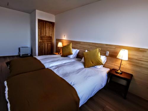 1 cama grande en una habitación de hotel con 2 lámparas en Fujio Pension Madarao Apartment Hotel & Restaurant, en Iiyama