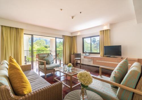 Radisson Resort and Suites Phuket في شاطئ كامالا: غرفة معيشة بها أريكة وتلفزيون
