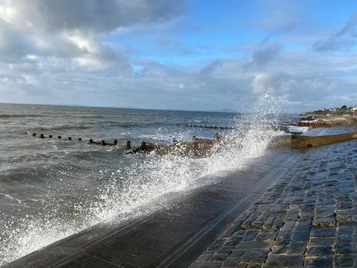 a large splash of water on a sidewalk next to the ocean at Stunning Pet-Friendly Home with Hot Tub less than one minute walk from Barmouth Beach in Barmouth