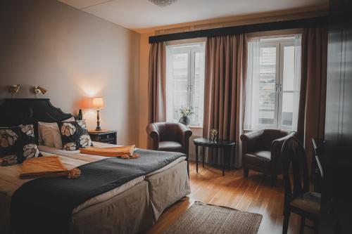 a bedroom with a bed and two chairs and a window at Mojo Hotell in Örebro