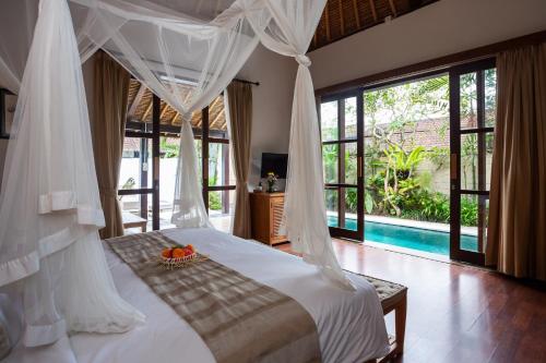 a bedroom with a bed with a canopy and a pool at Bije Suite Villa Ubud in Ubud