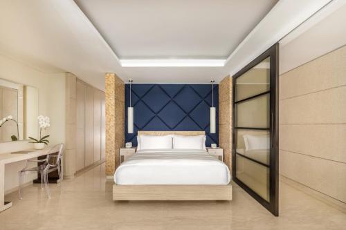 a bedroom with a bed and a desk and a mirror at COMO Uma Canggu in Canggu