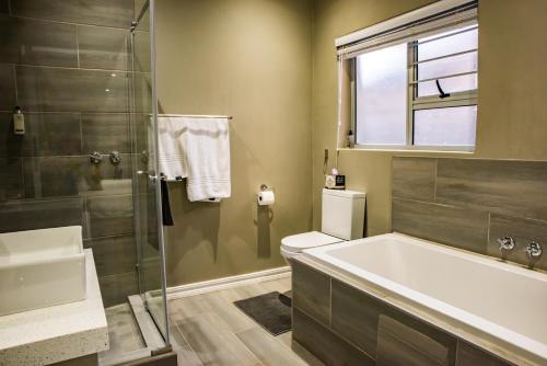 uma casa de banho com uma banheira, um WC e um chuveiro em Vanilla Guesthouse em Joanesburgo