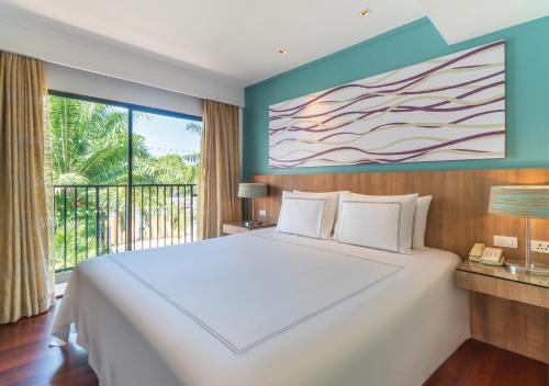 ein Schlafzimmer mit einem großen weißen Bett und einem Balkon in der Unterkunft Radisson Resort and Suites Phuket in Kamala Beach