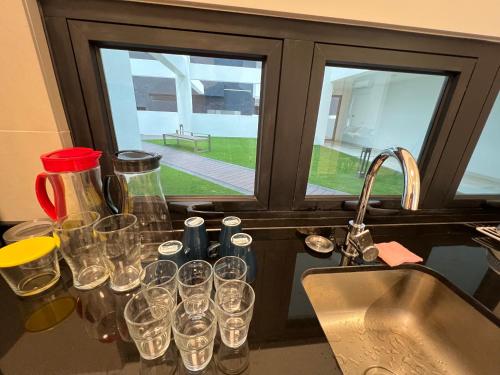 a bunch of glasses sitting on a counter next to a sink at Duplex Town House at EcoBotanic Near Legoland with Netflix and KTV System in Nusajaya