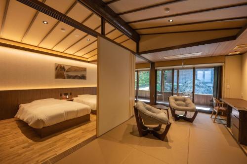 a bedroom with a bed and a desk and chairs at Rankeisou in Sanjo