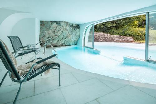 a room with a pool with two chairs and a table at Casa Las Caglias in Flims