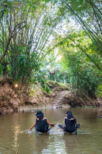 Ban Lam Ru (1)にあるkhaolakcampingの二人が川の中の椅子に座っている