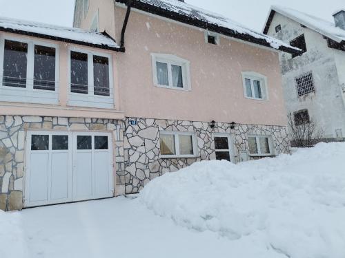 a house with a white garage in the snow at Apartment Kalpačina in Žabljak