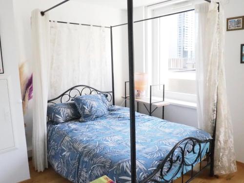 - une chambre avec un lit à baldaquin noir et des draps bleus dans l'établissement Les Halles : Studio Cosy et Moderne, à Strasbourg