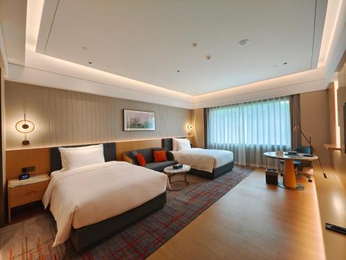 a hotel room with two beds and a couch at Wyndham Grand Zhaoqing Downtown in Zhaoqing