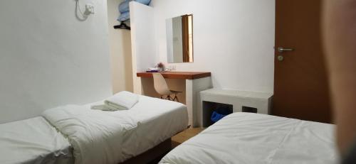 Habitación con 2 camas, escritorio y espejo. en Tang Hotel en Alor Setar