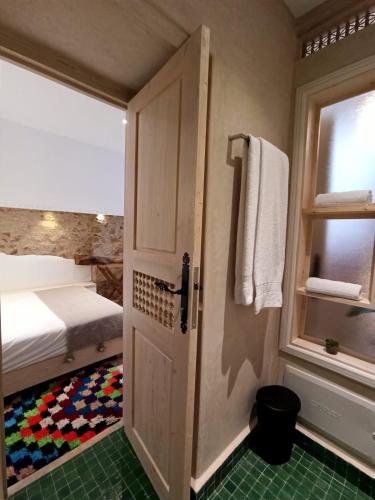 a bedroom with a bed and a door with a window at Dar YAMAR in Essaouira
