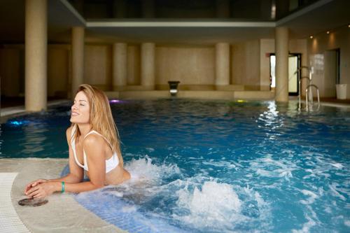 a young woman sitting in a swimming pool at Iberostar Waves Royal Andalus in Chiclana de la Frontera
