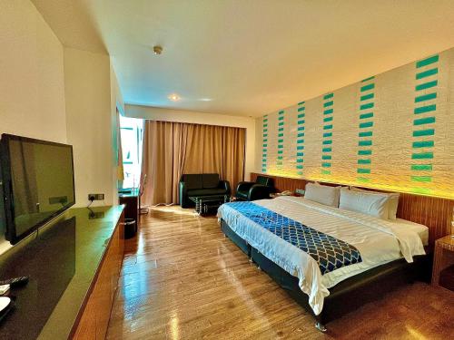 ein Hotelzimmer mit einem Bett und einem Flachbild-TV in der Unterkunft New World Express Motel in Bintulu