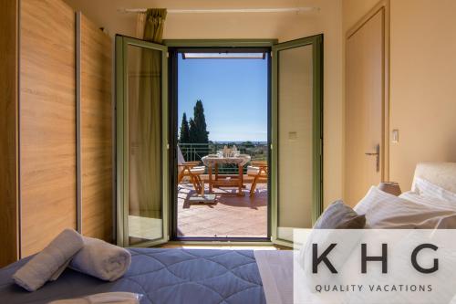 een slaapkamer met een bed en uitzicht op een patio bij Villa Elaionas 1 Experiencing nature's tranquility! in Svoronata