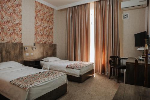 a hotel room with two beds and a desk at Omar Khayyam Hotel in Bukhara