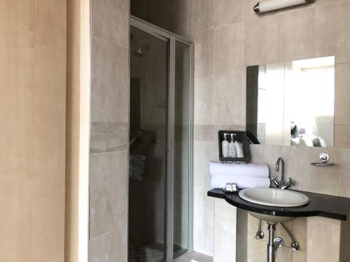 a bathroom with a sink and a shower with a mirror at Lovely 2 Storey apartment with pool, gym and bar in Johannesburg