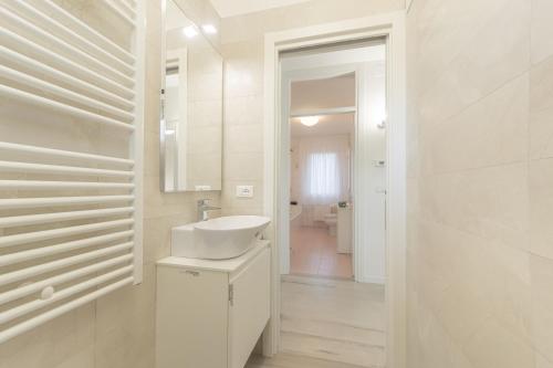ein weißes Badezimmer mit einem Waschbecken und einem Spiegel in der Unterkunft Da Nonna Antonia in Martellago