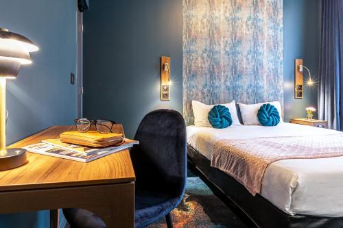 a hotel room with a bed and a desk with a desk at Hotel Glasgow Monceau by Patrick Hayat in Paris