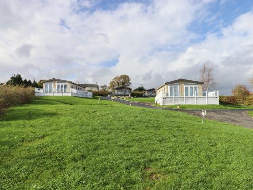 a grassy field with two houses in the background at Cherry Lodge in Newton Abbot