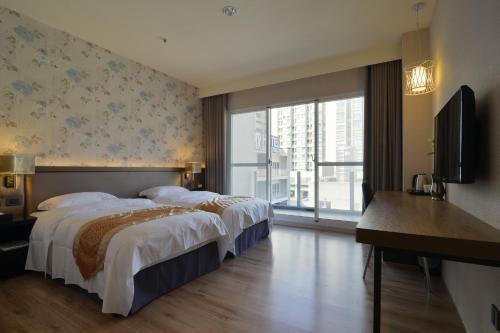 a hotel room with two beds and a television at Grand Crystal Hotel in Hsinchu City