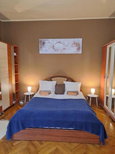 1 dormitorio con 1 cama grande con manta azul en Széll 3 Apartman, en Szombathely