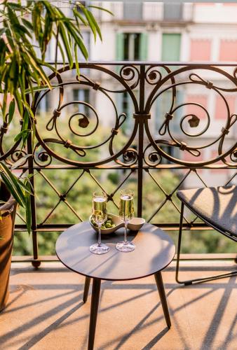 two glasses of wine on a table on a balcony at Hotel Casa Sagnier in Barcelona