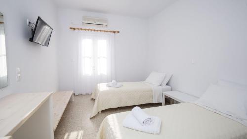 a white room with two beds and a tv at Hotel Galini Sifnos in Apollonia
