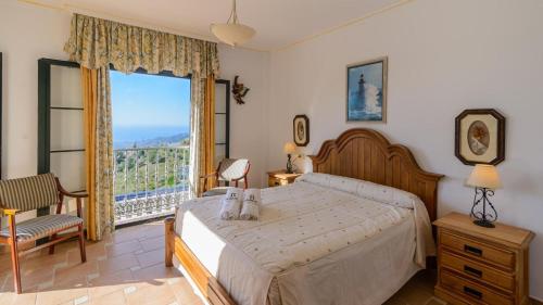 a bedroom with a bed and a large window at Villa el Pedregal Frigiliana by Ruralidays in Frigiliana