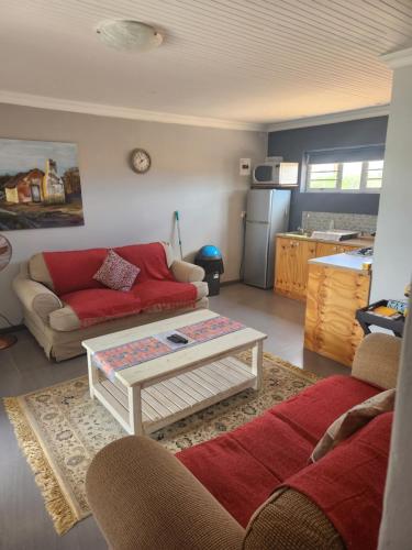 a living room with a red couch and a table at Volgenoeg Self Catering in Oudtshoorn