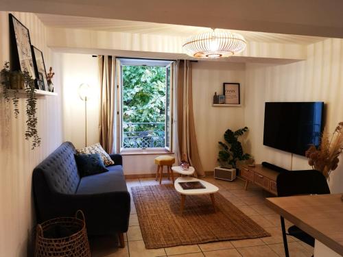 uma sala de estar com um sofá azul e uma televisão em Oasis de 42 m2 I Cosy I Cœur de ville I Lit 160x200 em Vaison-la-Romaine