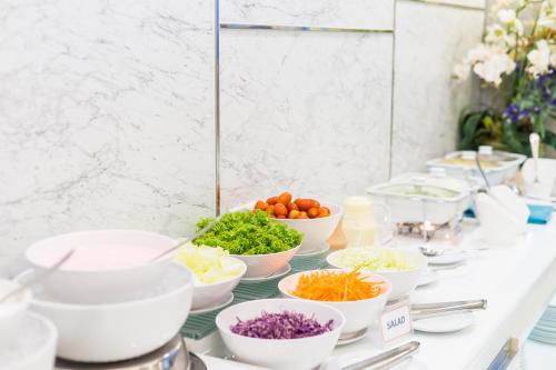 a buffet with bowls of vegetables on a table at Hotel De Bangkok in Bangkok