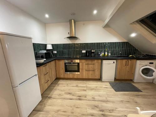 une cuisine avec des armoires en bois et un réfrigérateur blanc dans l'établissement Les appartements d’Edgar, à Bourges