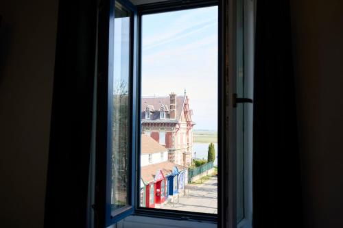 an open window with a view of a building at The Originals Boutique, Hôtel La Colonne de Bronze, Saint-Valéry-sur-Somme in Saint-Valery-sur-Somme