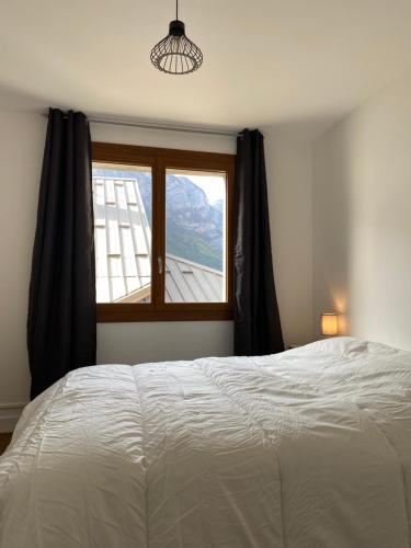 ein Schlafzimmer mit einem großen Bett und einem Fenster in der Unterkunft Appartement Le Lauzet in La Roche-de-Rame