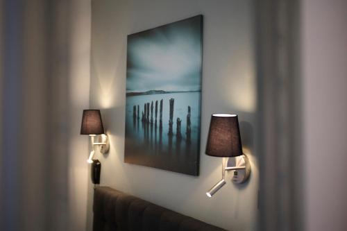 a room with two lamps and a painting on the wall at The Originals Boutique, Hôtel La Colonne de Bronze, Saint-Valéry-sur-Somme in Saint-Valery-sur-Somme